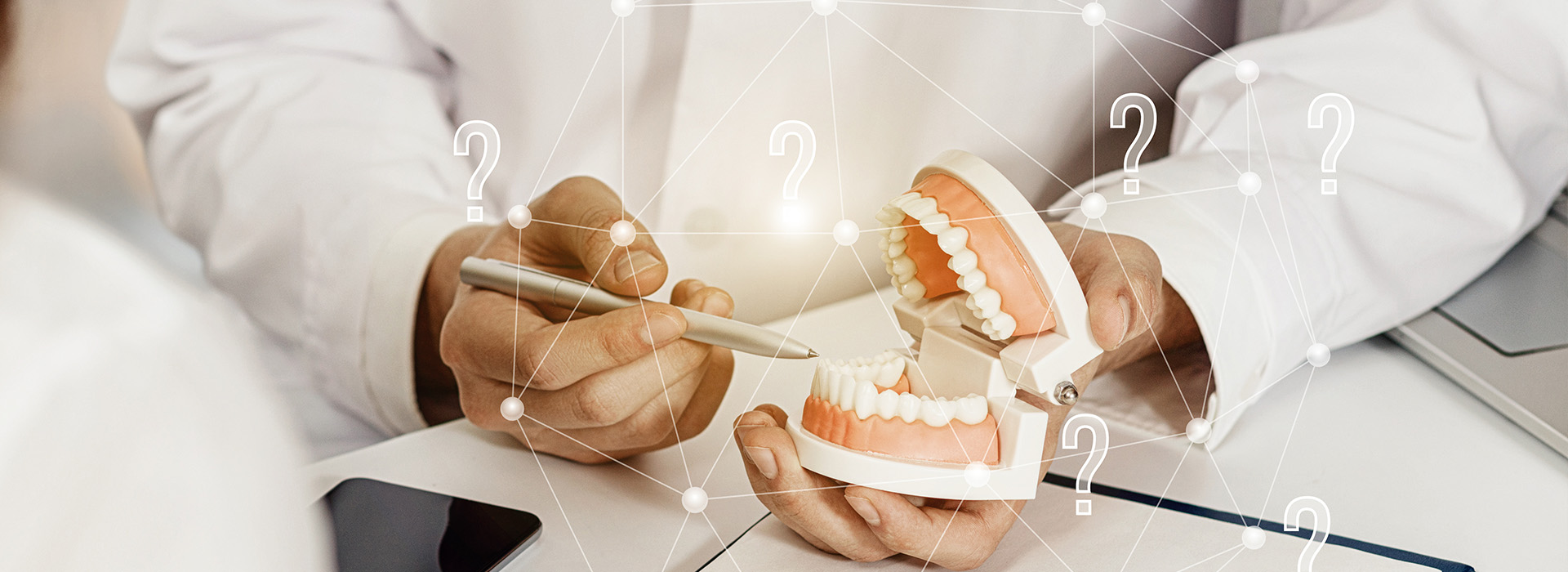 The image shows a person holding a dental model with a focus on the teeth, possibly in a dental or medical setting.