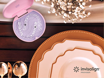 The image displays a collection of tableware, including plates and bowls, arranged on a wooden surface with a pink and purple toothbrush holder in the center.