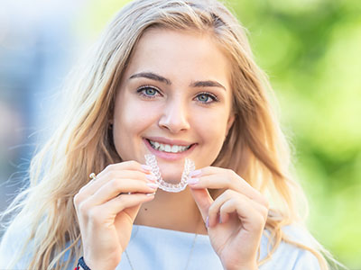 Smiling woman holding a toothbrush, showcasing dental care product.