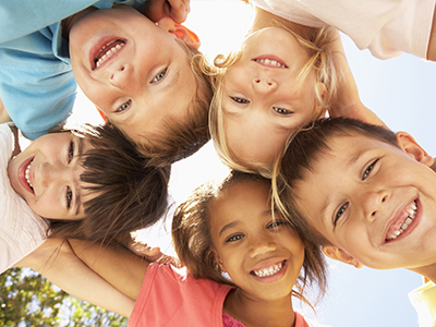 Children s group portrait with smiles, taken outdoors on a sunny day.